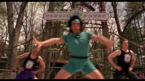 A Man Stands In Front Of A Sign That Says Perkis Power GIF