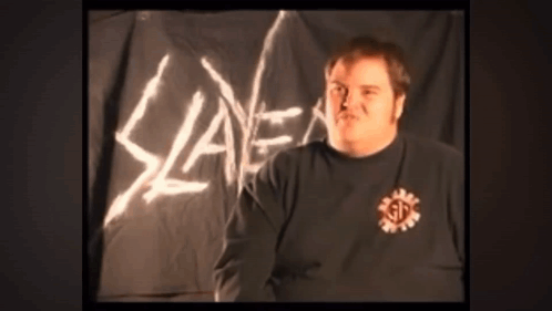 A Man Stands In Front Of A Slayer Sign GIF
