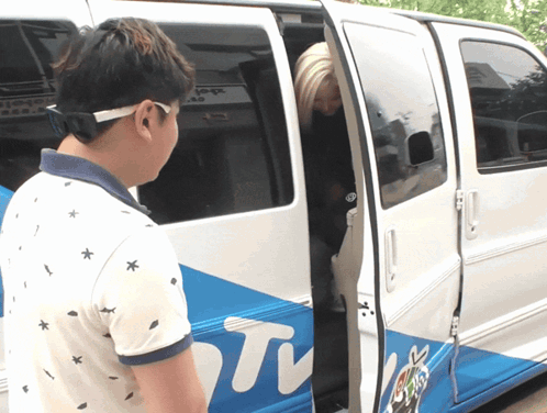 A Man Stands In Front Of A Van That Says ' Tv ' On The Side GIF