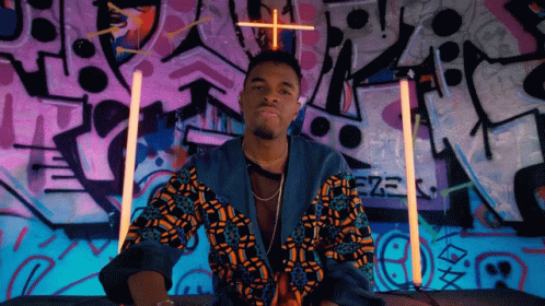 A Man Stands In Front Of A Wall That Has Graffiti On It And The Word Eze On It GIF