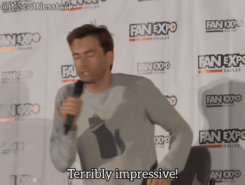A Man Stands In Front Of A Wall That Says Fan Expo Dallas GIF