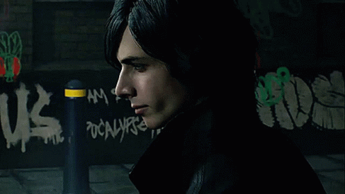 A Man Stands In Front Of A Wall With Graffiti That Says Us GIF