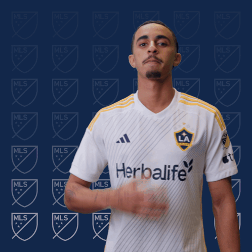 A Man Stands In Front Of A Wall With Mls Logos GIF