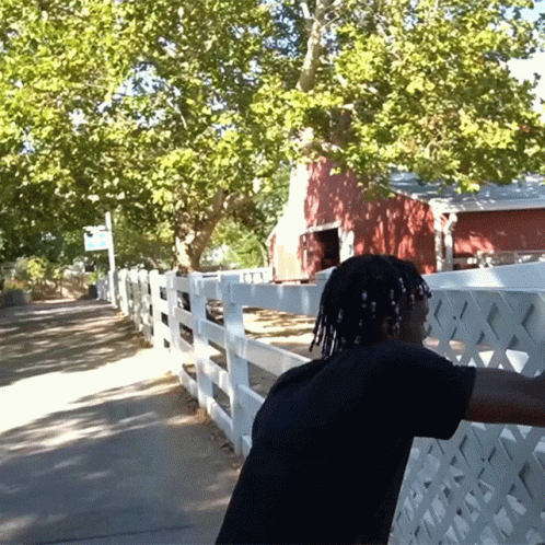 A Man Stands In Front Of A White Picket Fence GIF