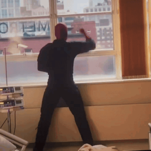 A Man Stands In Front Of A Window With A Sign That Says Optimum GIF