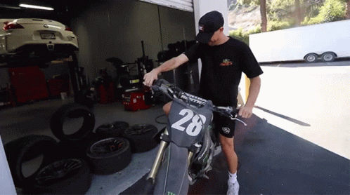 A Man Stands Next To A Motorcycle With The Number 28 On The Front GIF
