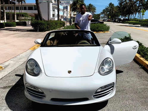 A Man Stands Next To A White Porsche Convertible GIF