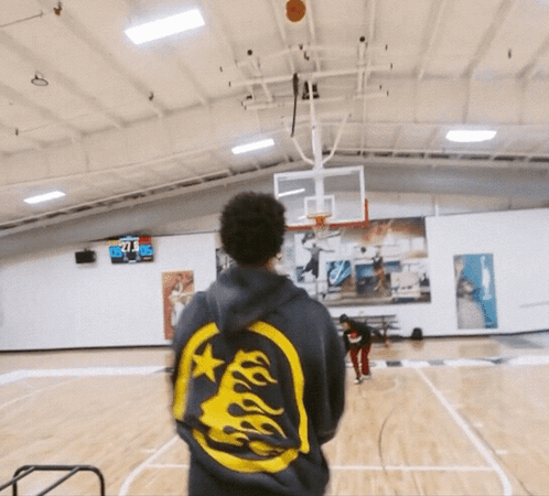 a man stands on a basketball court wearing a hoodie with flames on it and the number 71 on the back