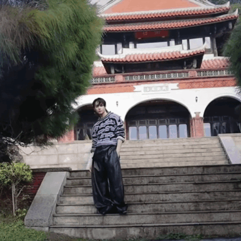 A Man Stands On A Set Of Stairs In Front Of A Building With Chinese Writing GIF