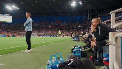 A Man Stands On A Soccer Field With A Sign That Says Stadium On It GIF