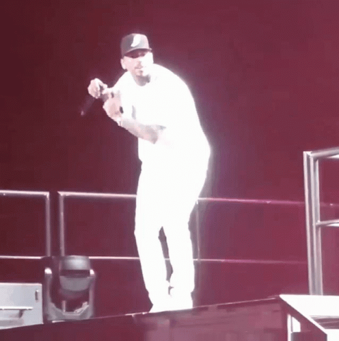 A Man Stands On A Stage Holding A Microphone In His Hand GIF
