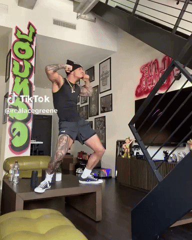Man Standing On One Leg In Front Of Graffiti GIF