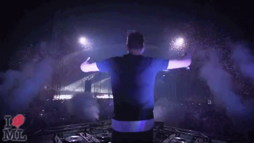 A Man Stands On Stage With His Arms Outstretched In Front Of A Crowd And A Sign That Says " I Love Mil " GIF