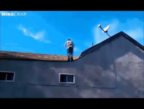 a man stands on the roof of a building with a satellite dish on top of it