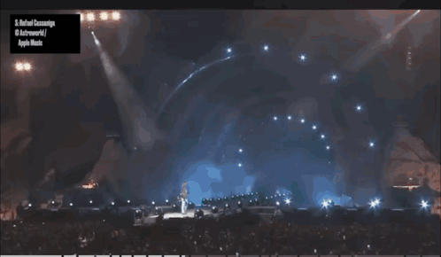 A Man Stands On Top Of A Stage With A Sign That Says Apple Music GIF