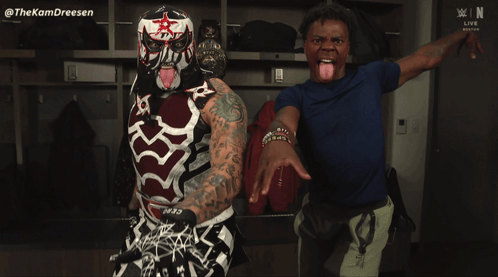 A Man Sticking His Tongue Out Next To A Wrestler With A Mask On GIF
