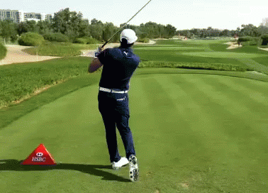 A Man Swinging A Golf Club On A Golf Course With A Hsbc Sign In Front Of Him GIF