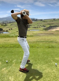 A Man Swings A Golf Club At A Golf Ball GIF