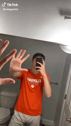 A Man Taking A Picture Of Himself In A Mirror With His Hands In The Air GIF