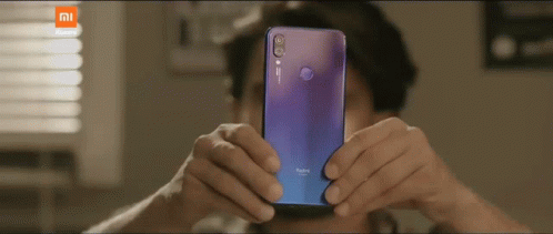 A Man Taking A Picture With A Purple Redmi Phone GIF