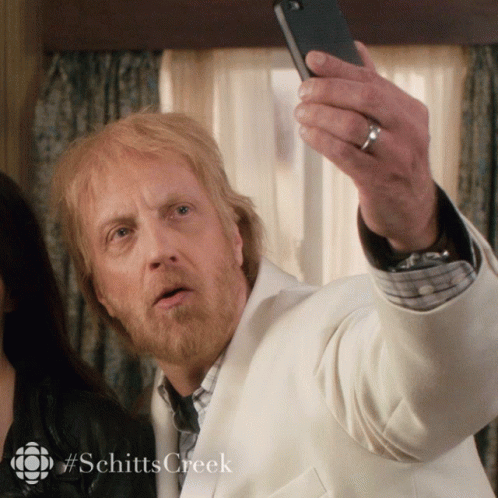A Man Taking A Selfie With #Schittscreek Written On The Bottom GIF