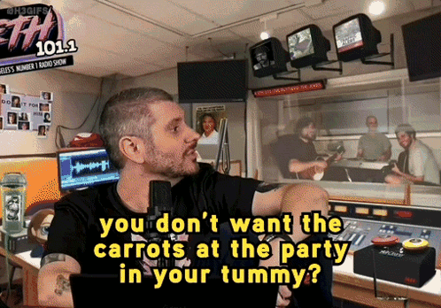 A Man Talking Into A Microphone In Front Of A Sign That Says 101.1 GIF
