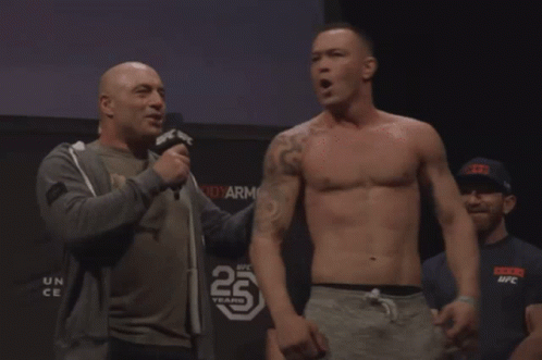 A Man Talking Into A Microphone In Front Of A Sign That Says 25 Years On It GIF