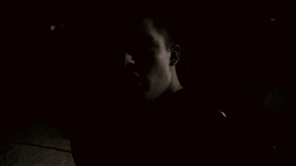 A Man Talking On A Cell Phone In A Dark Room GIF