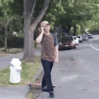 A Man Talking On A Cell Phone While Walking Down A Street GIF
