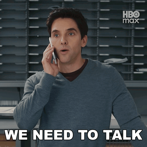 a man talking on a cell phone with the words we need to talk behind him