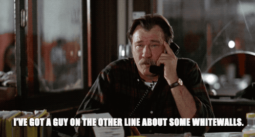 A Man Talking On A Phone With The Words " I 'Ve Got A Guy On The Other Line About Some Whitewalls " Below Him GIF
