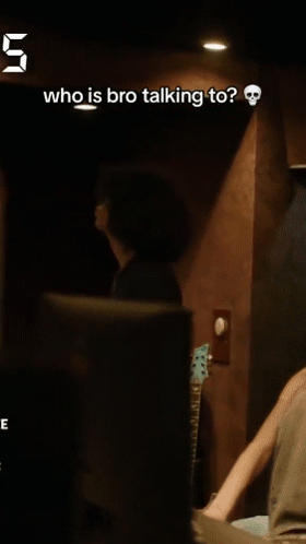 a man talking to another man in a dark room with the number 5 above him