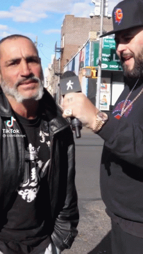 A Man Talking To Another Man With A Microphone That Says Tiktok On The Bottom GIF