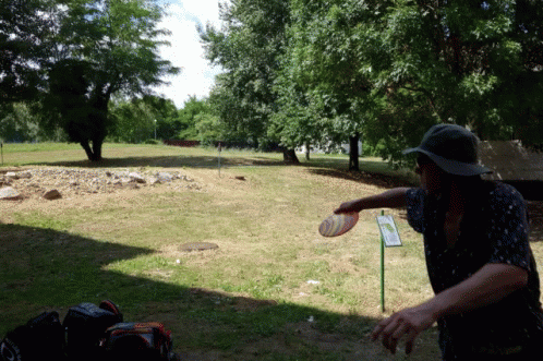 a man throwing a frisbee in a park with a sign that says ' a few steps ' on it