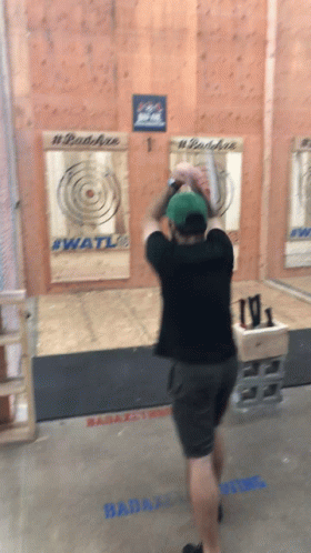 A Man Throws An Axe In Front Of A Wall That Has #Badaxe On It GIF