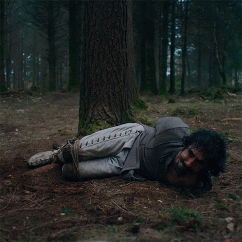 A Man Tied To A Tree With Stitches On His Pants GIF