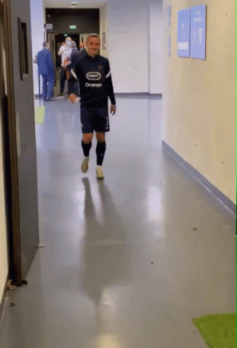 A Man Walking Down A Hallway With A Shirt That Says Orange On It GIF