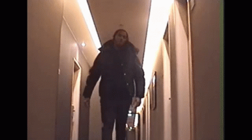 A Man Walking Down A Hallway With The Number 10 On The Wall Behind Him GIF