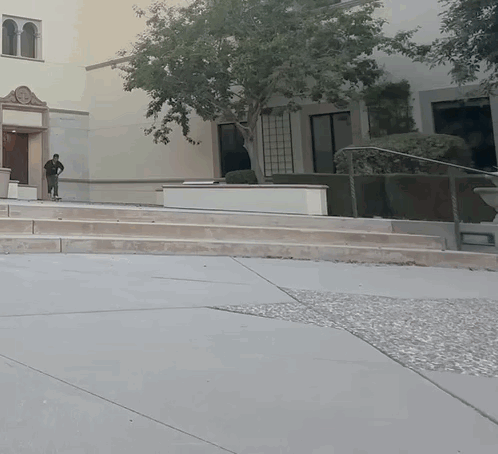 A Man Walking Down A Set Of Stairs In Front Of A Large Building GIF