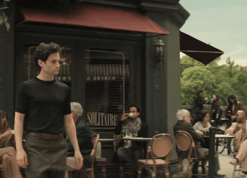 A Man Walking In Front Of A Solitaire Store GIF
