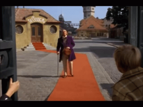 A Man Walking On A Red Carpet In Front Of A Building With The Word Wonka On It GIF