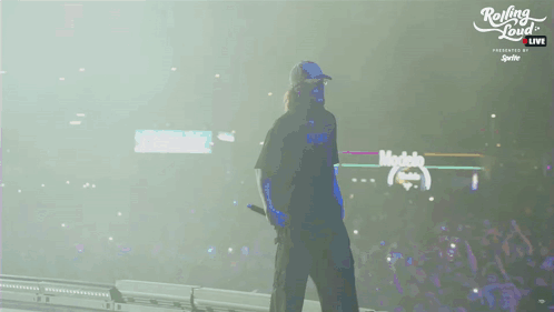 A Man Walking On A Stage With Rolling Loud Written On The Bottom GIF