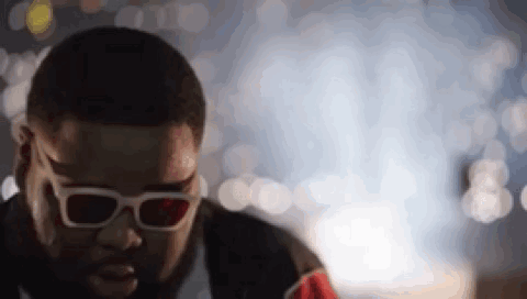 A Man Wearing 3D Glasses Is Looking Down At Something . GIF