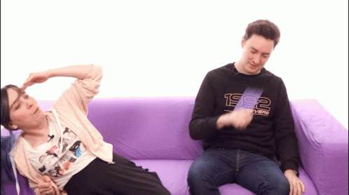 A Man Wearing A 1992 Sweatshirt Sits Next To A Woman On A Couch GIF