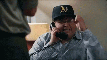 A Man Wearing A A 'S Hat Is Talking On A Phone GIF