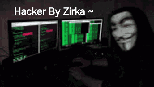 a man wearing a anonymous mask is sitting in front of a computer monitor .