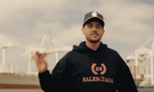 A Man Wearing A Balenciaga Hoodie And A Baseball Cap GIF