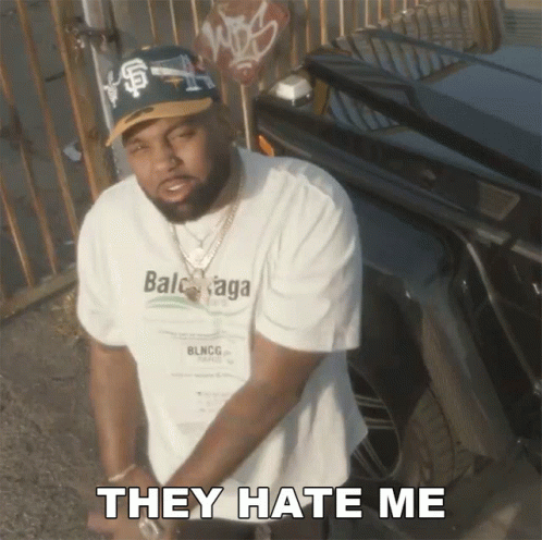 A Man Wearing A Balenciaga Shirt Is Standing In Front Of A Car And Says They Hate Me GIF