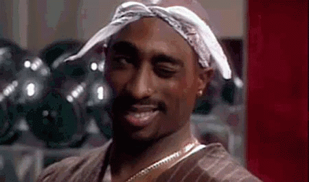 A Man Wearing A Bandana And A Necklace Is Smiling . GIF