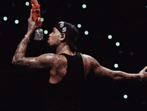 A Man Wearing A Bandana With The Number 99 On It Holds A Bottle Of Water In His Hand GIF